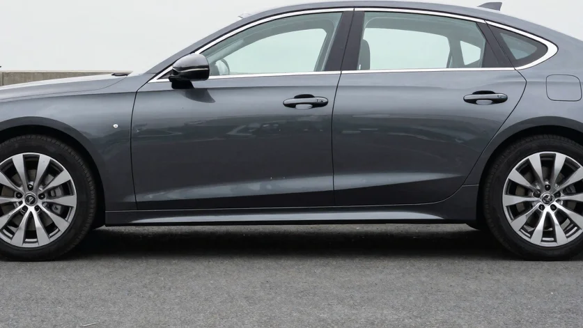 Exterior shot of a sleek, dark grey sedan, clean overcast daylight, sharp focus.